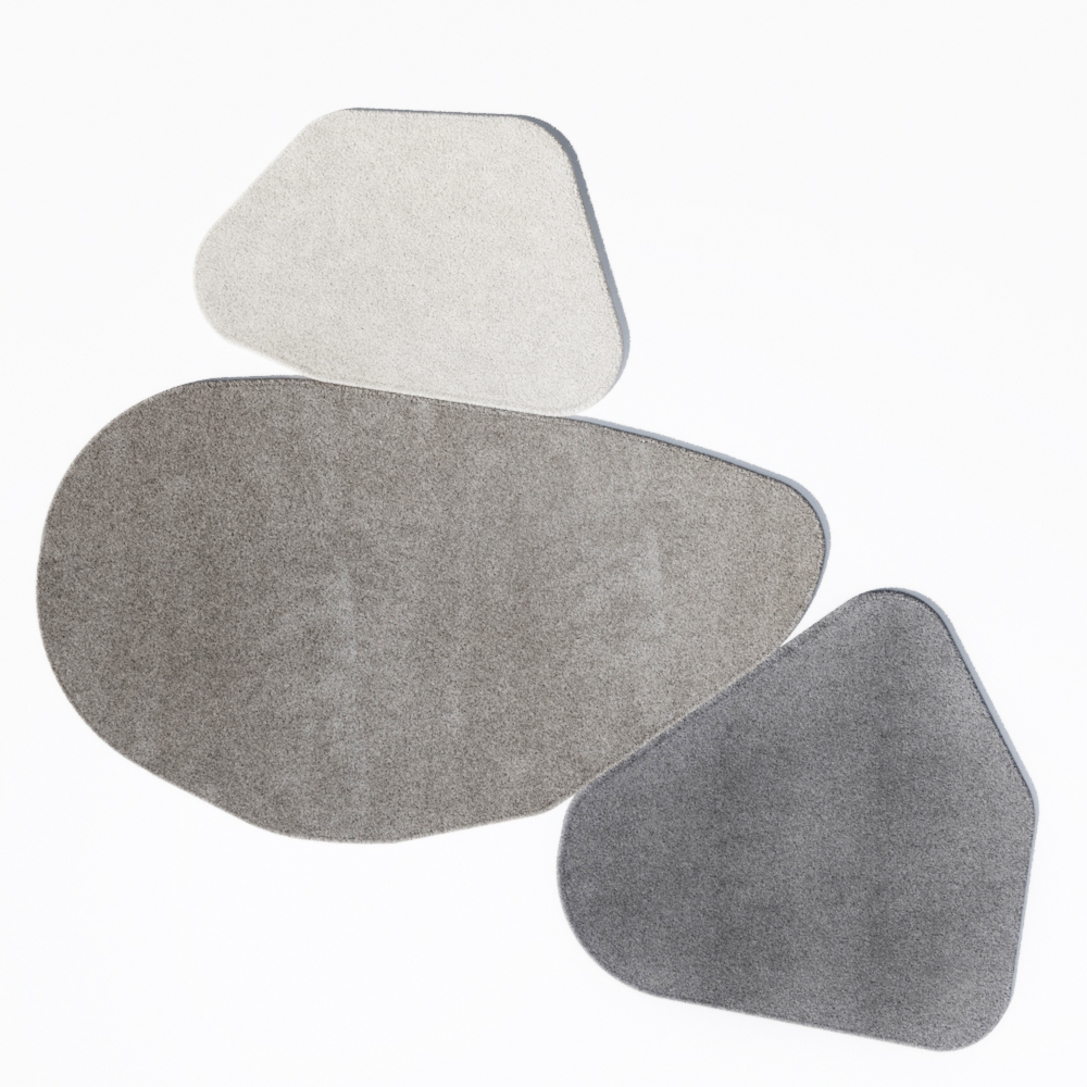 Composizione di tre tappeti sagomati a forma di sasso in diverse sfumature di grigio e beige.