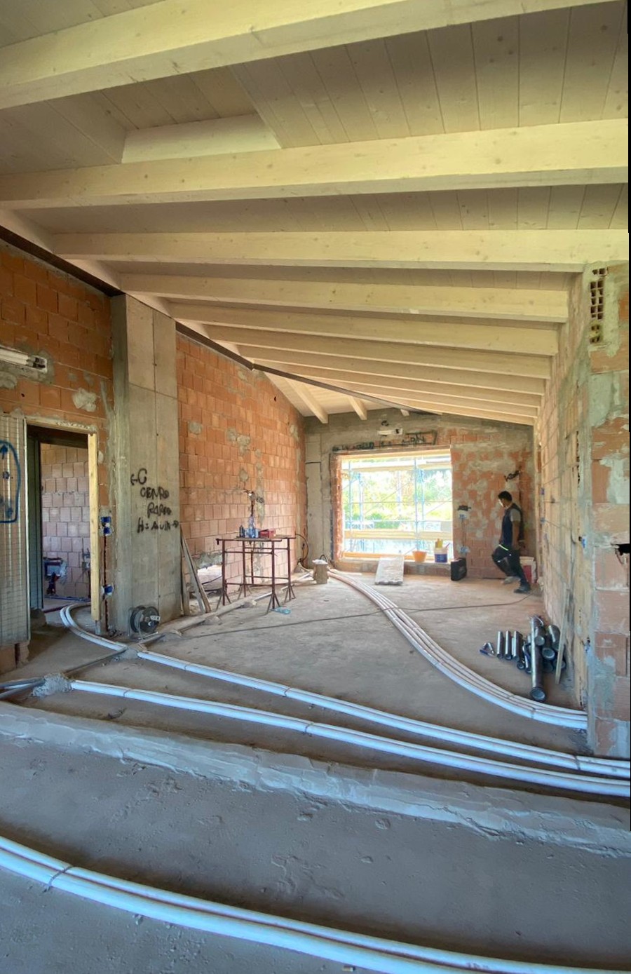 foto di un cantiere, con tubi sul pavimento e pareti senza intonaco