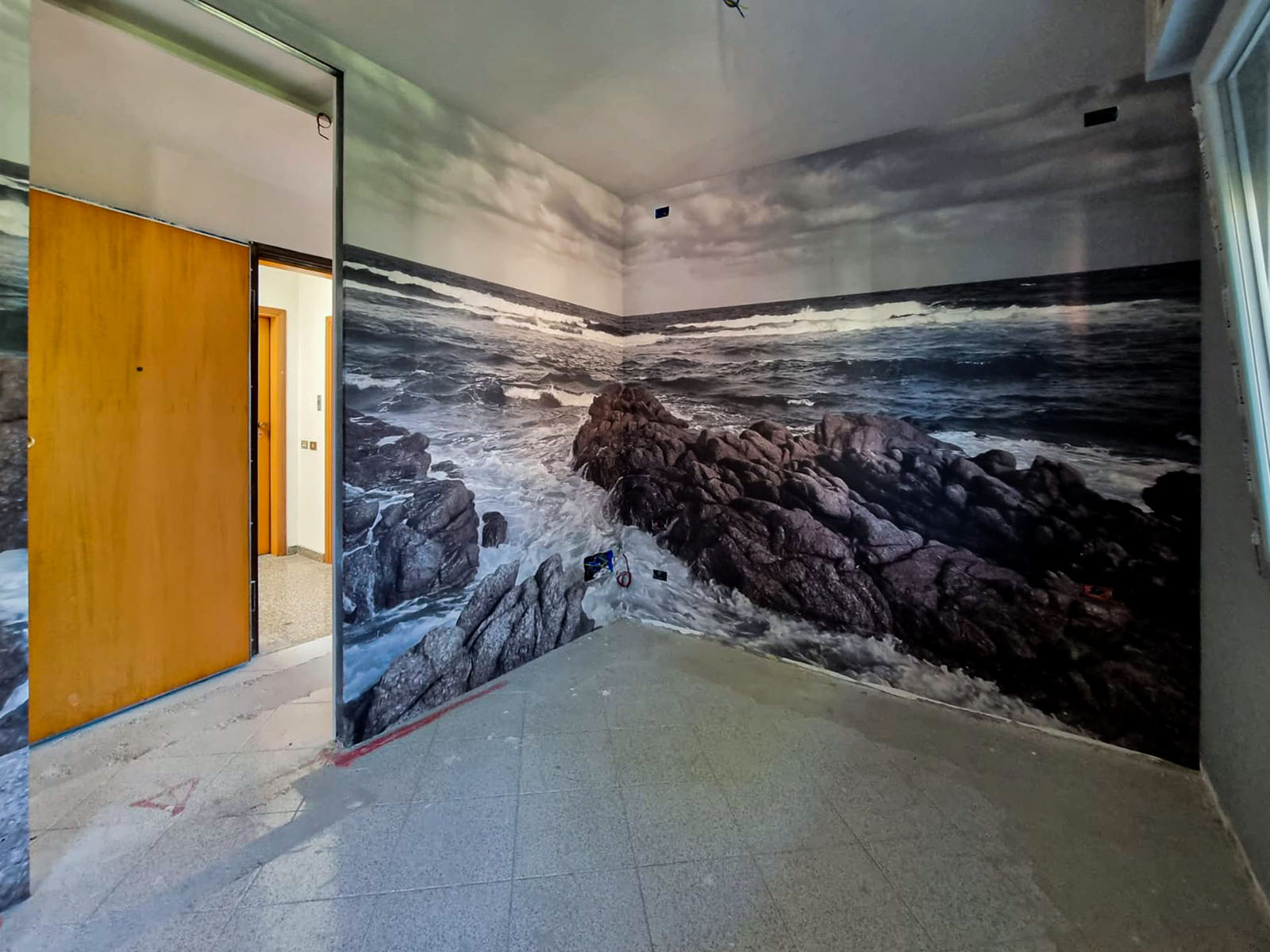 Interior design di una camera matrimoniale realizzata in Versilia. una carta da parati con una scena marina fa da sfondo a due pareti della camera rendendo la percezione tridimensionale
